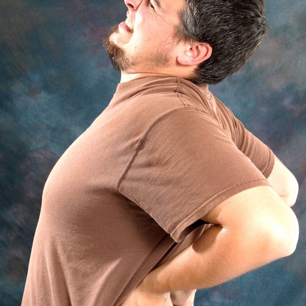 Man with back pain massages his back trying to relieve his backache.
